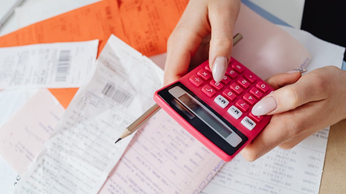 Calculator, coins and a house key on property documents representing conveyancing search costs