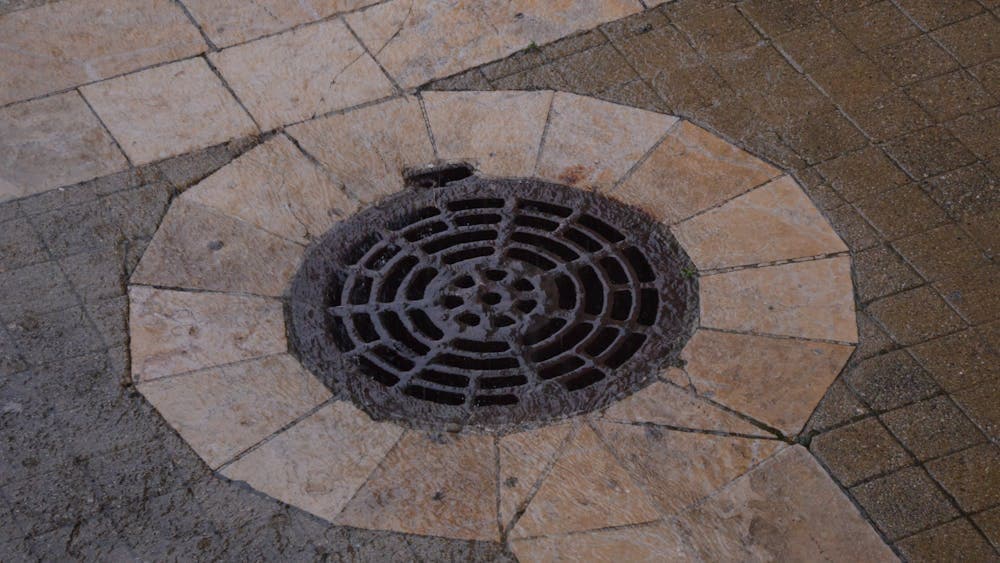 A residential street showing a drainage manhole cover and kerbside water infrastructure