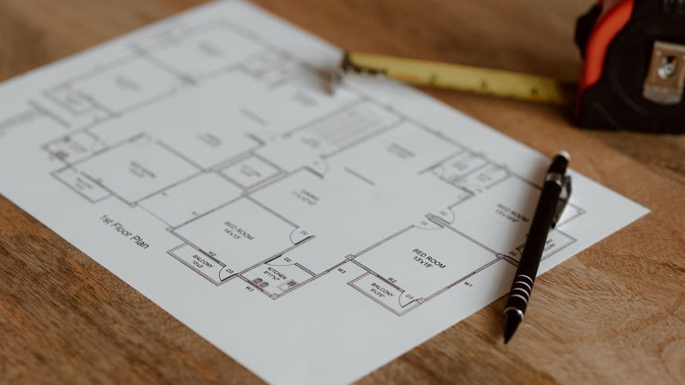 A planning officer reviewing site drawings and a location map at a desk